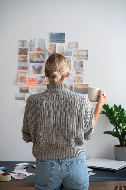 female designer looking at mood board on a wall